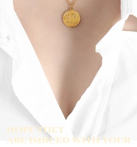 Détail d'un collier pendentif vague doré porté sur une chemise blanche style romantique