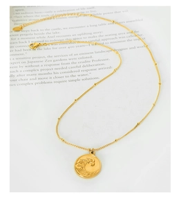Détail du collier chaîne satellite dorée avec pendentif rond gravé d'un motif de vague