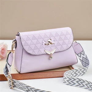 Détail du sac matelassé lilas avec pendentif aile doré et bandoulière tissée large