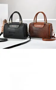 Detail of crocodile embossed Boston bags in black and brown with metal handles