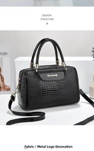 Close-up of black crocodile pattern faux leather texture with gold metal brand plaque