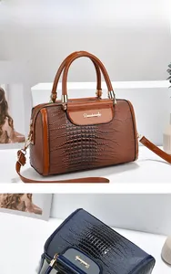 Detail of crocodile embossed boston bags in caramel and navy with metallic logos