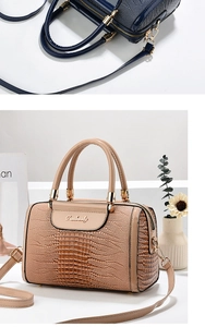 Detail of crocodile pattern faux leather handbag with golden hardware and handles