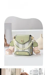 Detail of green crossbody bag with M logo, pearl handle and checkerboard pattern