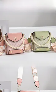 Detail of color-block flap bags with pearl handles and logo plaque on a modern pedestal