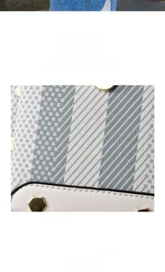 Detail view of geometric fabric texture and white PU leather with gold rivets on handbag