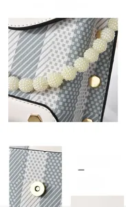 Close-up of retro plaid handbag with pearl handle and golden magnetic buckle detail