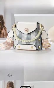 Close-up of contrast crossbody bag with pearl handle and printed wide shoulder strap