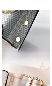 Detail view of leather bag showing gold hexagonal rivets and H-pattern woven strap