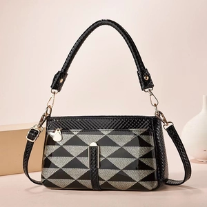 Detail of black and silver geometric pattern handbag with glossy finish and metal buckles