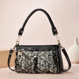 Detail of black faux crocodile leather handbag with sturdy handle and detachable strap