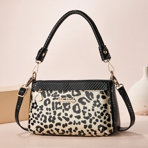 Detail of leopard print handbag with golden brand name plate and black snake leather texture