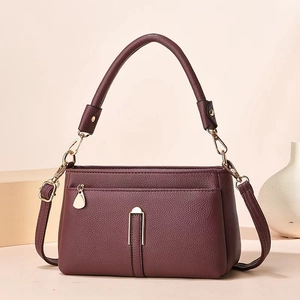 Close-up of litchi texture burgundy shoulder bag with golden metal hardware detail