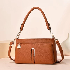 Macro detail of brown lychee pattern leather shoulder bag with metallic U-shaped buckle