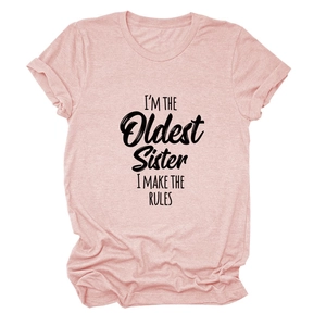 Gros plan sur l'imprimé noir I'M THE OLDEST SISTER sur un t-shirt rose