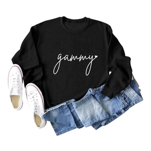 Flat lay of black round neck sweatshirt with gammy print and white canvas sneakers