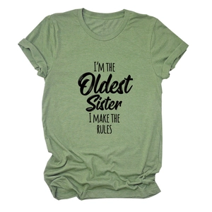 Gros plan sur la texture du tissu vert avec l'inscription 'I'M THE OLDEST SISTER'