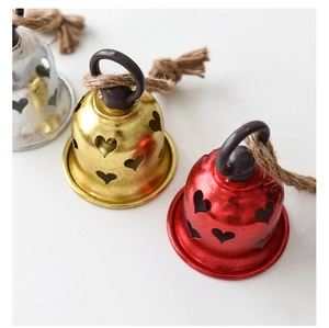 Close-up of metal Christmas bells with heart cutouts and rustic hemp rope hangers