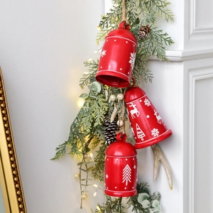 Three red Christmas iron bells with white reindeer prints hanging on a rustic hemp rope