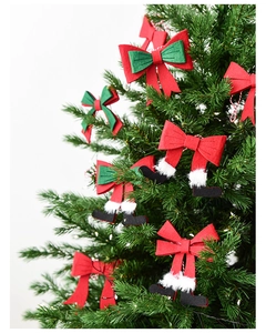 Detail of Christmas bow ornaments and felt Santa boots hanging on a festive tree
