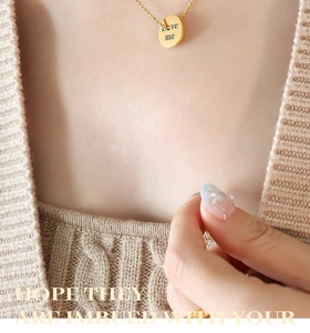 Detail of 18K gold plated bead chain necklace featuring an engraved Love Me round pendant