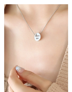 Detailed view of bead chain necklace with engraved Love me round pendant on neck