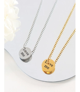 Detail of gold and silver Love Me engraved round pendant necklaces on a mirror