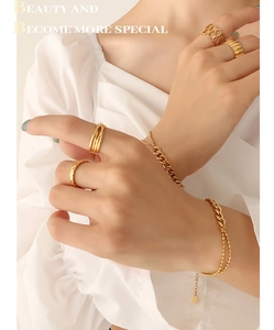 Detailed view of layered gold bead bracelets and geometric rings on model wrist