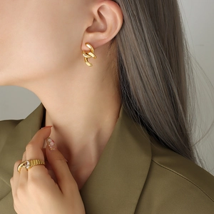Boucles d'oreilles chaînons dorés et bague avec diamant ovale sur costume vert foncé