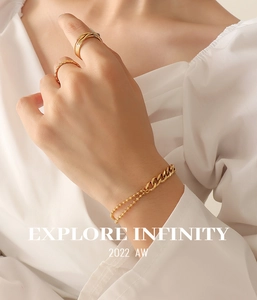 Detailed view of layered gold chain bracelet and rings on woman wearing white shirt