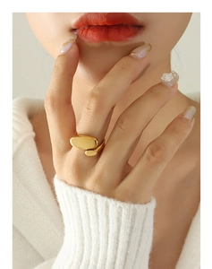 Irregular geometric open ring in gold finish on finger with white sweater background