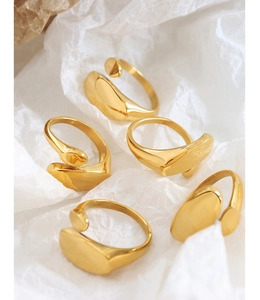 Close-up of five chunky minimalist irregular geometric gold rings on textured paper