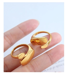 Detailed view of polished gold plated irregular open rings on finger with organic shape