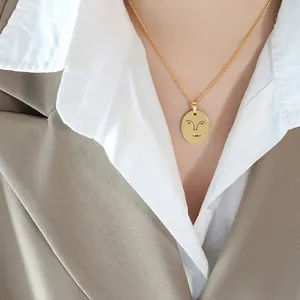 Collier avec pendentif ovale doré en acier titane et motif de visage abstrait minimaliste