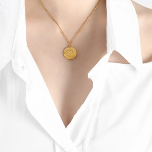 Élégant collier doré avec pendentif vague en relief porté au cou sur chaîne à billes