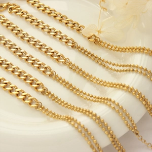 Five gold double-layer rice bead and Cuban chain necklaces on a white ceramic plate