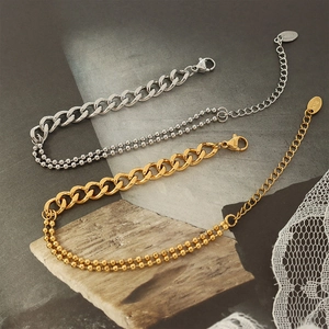 Two-layer gold and silver mixed Cuban and bead chain bracelets on a textured stone background