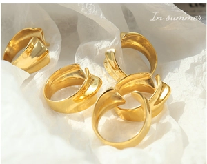 Set of minimalist irregular wave rings in gold finish on white textured paper