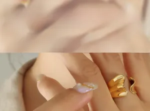 Close-up of golden irregular wavy open ring with a mirror polished finish on model