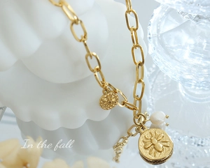 Macro view of vintage gold chain necklace with bee relief pendant and freshwater pearl