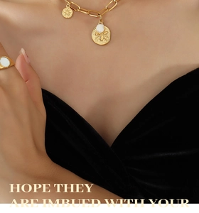 Detailed view of gold chain necklace with bee pendant and freshwater pearl on black velvet