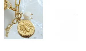 Detail of a vintage gold chain with a bee relief pendant and a baroque freshwater pearl