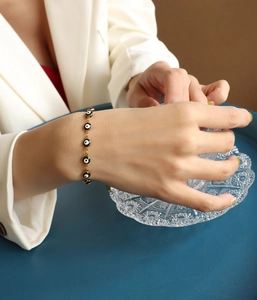 Dettaglio dei ciondoli malocchio su bracciale dorato con perline smaltate blu e nere