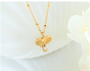 Detailed close-up of a golden elephant head pendant on a delicate bead chain