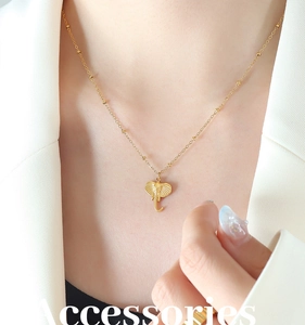 Detailed view of a gold elephant pendant necklace with a beaded satellite chain on a model