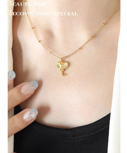 Detailed view of a gold elephant pendant necklace worn on a collarbone with beaded chain