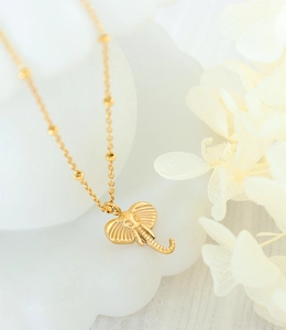 Macro shot of gold elephant pendant with textured ears and beaded necklace chain