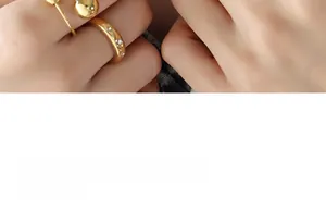 Close-up of gold starburst ring and double bead open ring set worn on finger