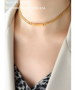 Close-up of golden curb chain choker with smooth curved metal plate on neck