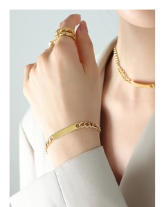 Detailed view of heavy gold plated geometric bar bracelet and textured ring on model